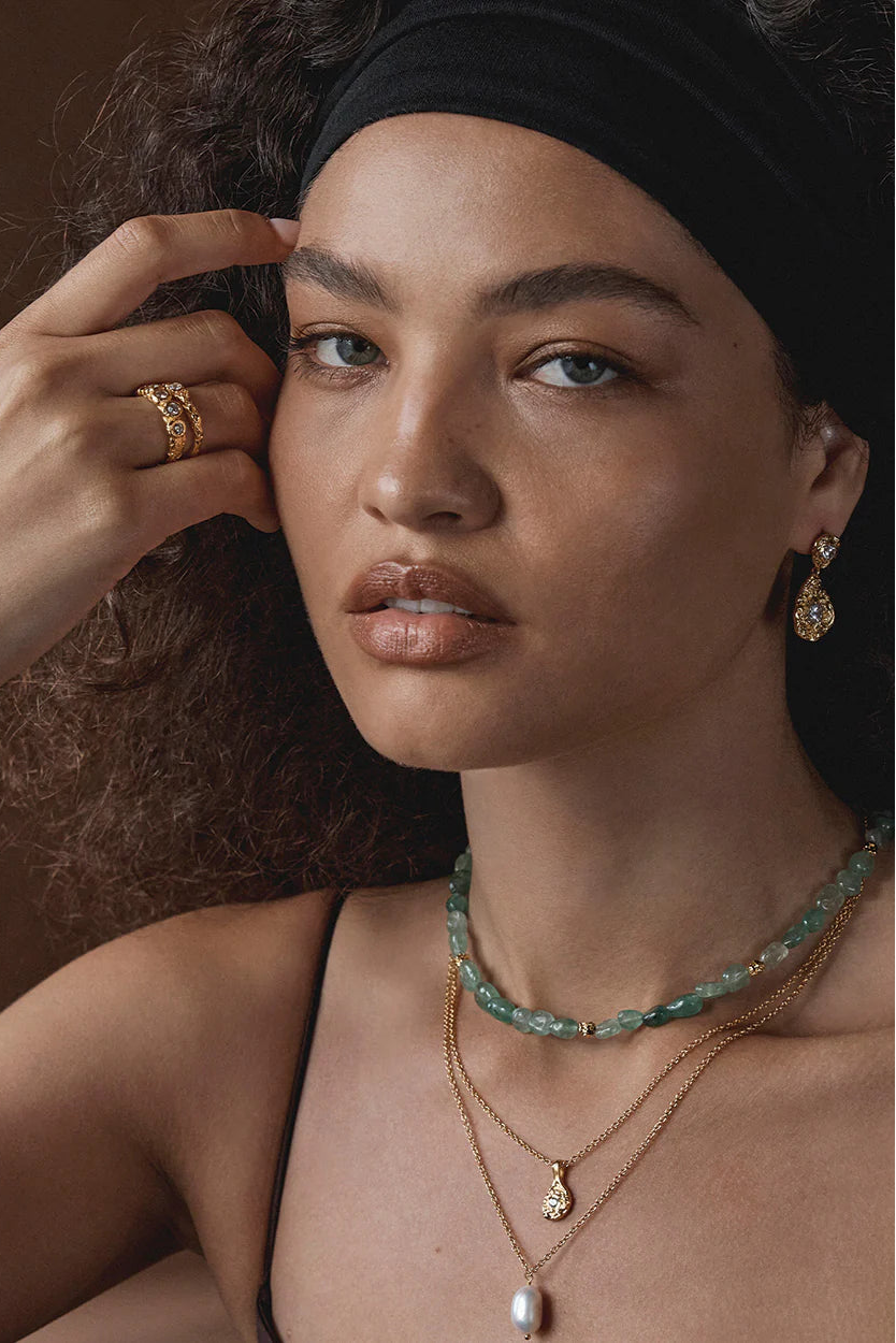 Woman wearing gold jewelry with a dark background