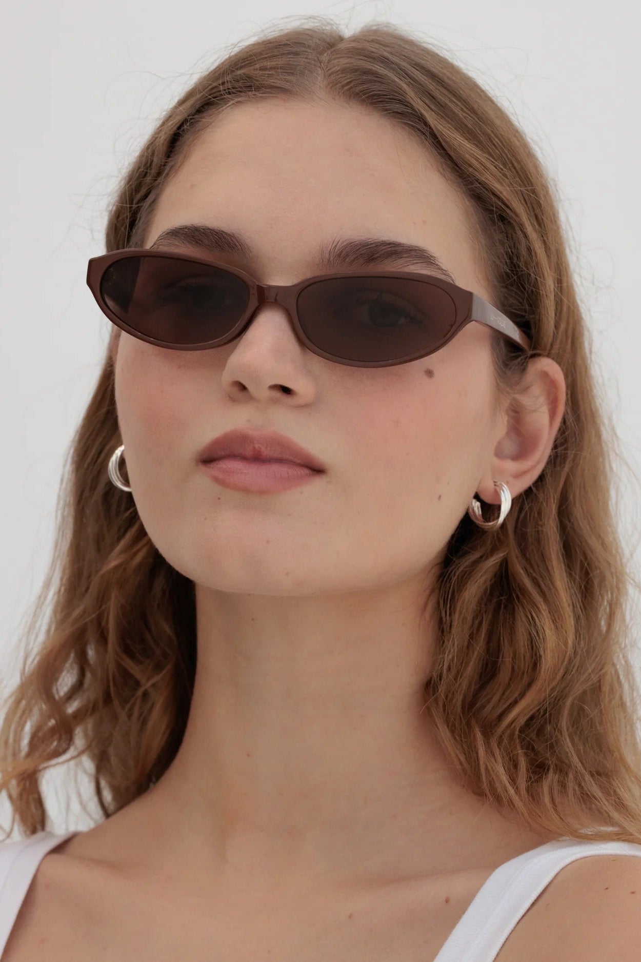 Woman wearing brown sunglasses with a white background