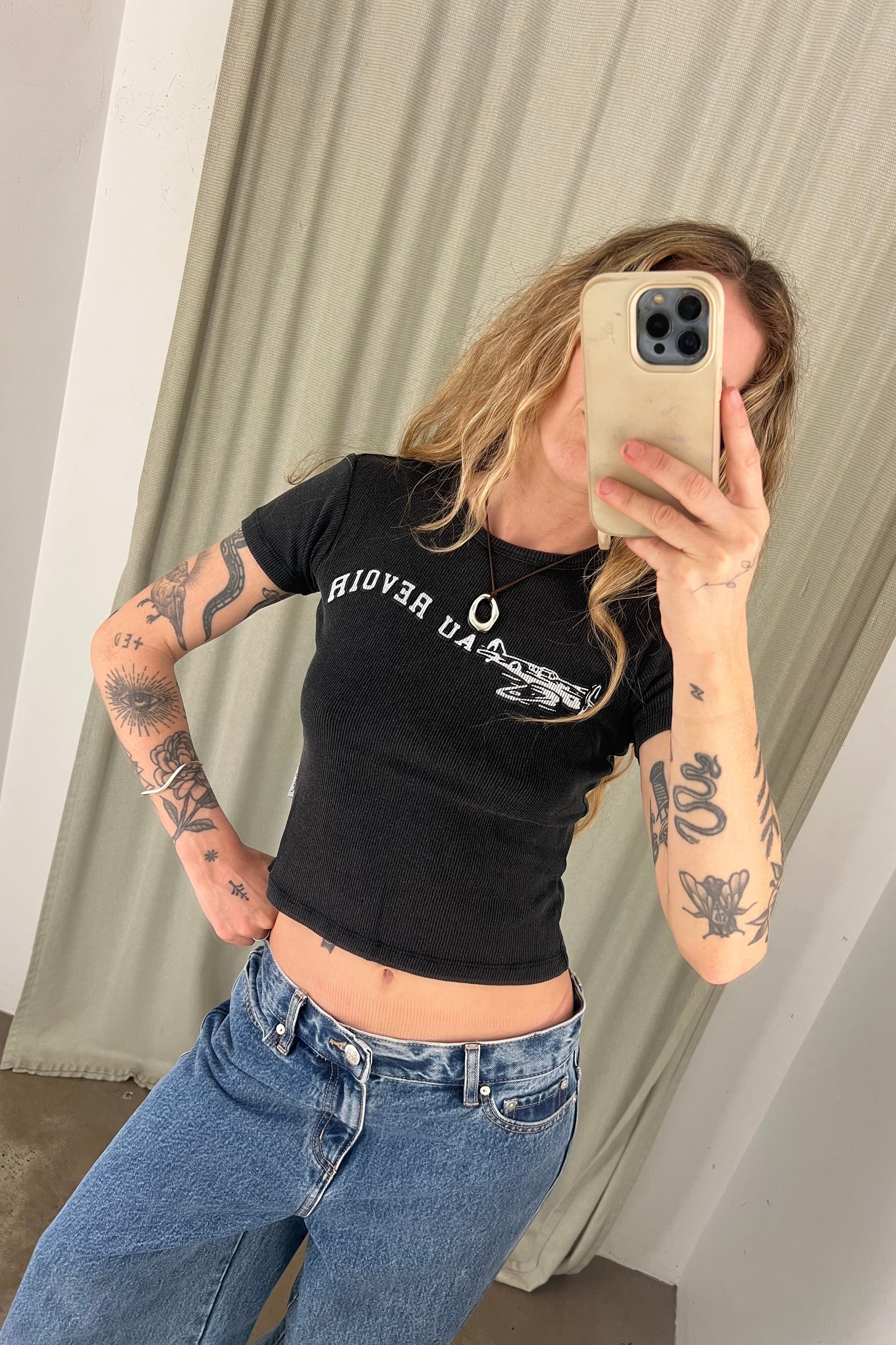 Person taking a mirror selfie wearing a black t-shirt and blue jeans.