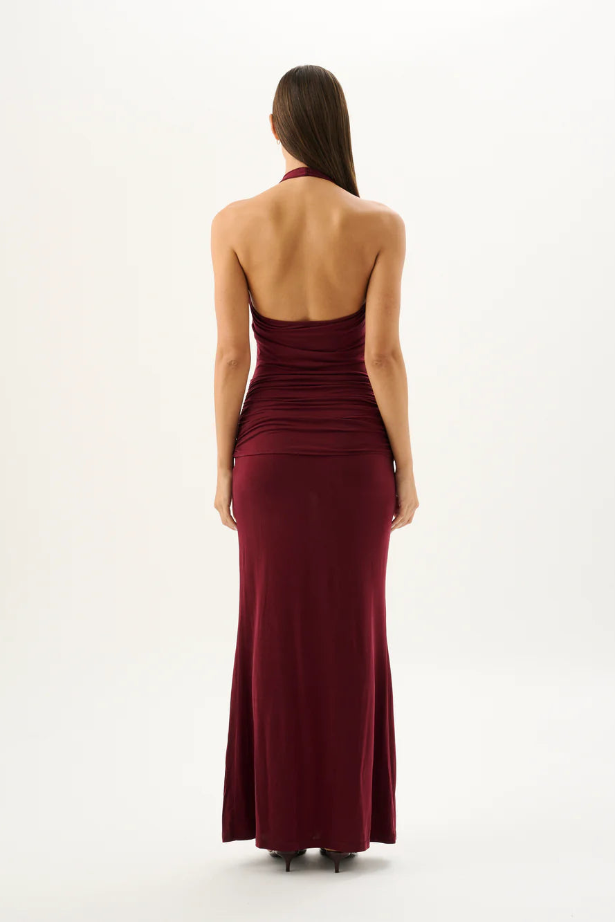 Woman wearing a burgundy halter neck gown on a white background